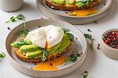 Sandwiches with avocado, poached egg, sprouts and cheese for healthy breakfast on white background. top view