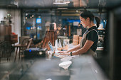 asian chinese female barista using laptop while enjoying dinner at coffee shop bar counter