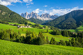 Green grassy meadows in the village of Santa Maddalena against the great peaks of the Odle Group, Val di Funes, Dolomites.