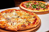 Pizza with salami, bell pepper, tomatoes and cheese, pickles, bacon and sausages on a light background. Close-up, selective focus