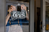 Close-up on a business owner hanging an open sign on the door of his restaurant