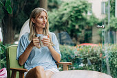 A young woman is sitting in a coffee shop near the window drinking coffee in the morning.