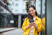 Female business professional walking outside and texting from her mobile phone.