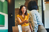 Cheerful businesswomen shaking hands in meeting room