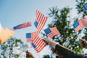 A group of people is waving small American flags at sunset