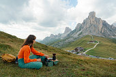 Woman brewing alternative coffee sitting with view of Passo Giau in Dolomites