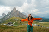 woman raising arms in awe on the background of Passo Giau in Dolomites