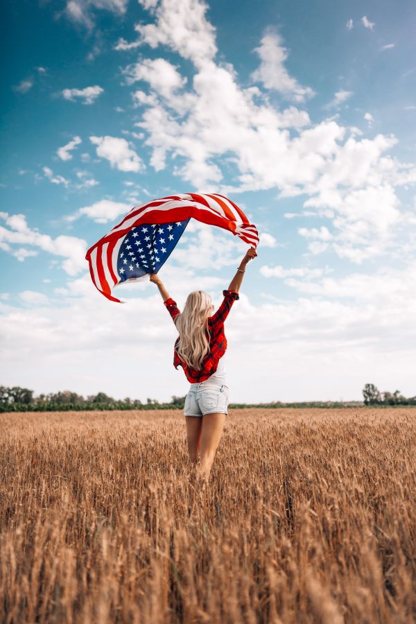 Woman Holding an American Flag in a Field Free Photo